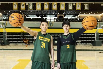 Mike Sharavjamts (right) and Junjie Wang of the USF Dons Basketball team